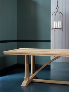 a wooden table sitting in front of a blue wall with three candles on top of it