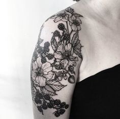 a woman's arm with flowers and berries tattooed on her left arm, in black and white