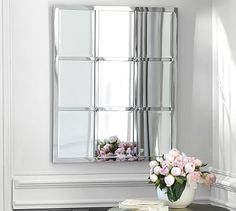 a vase filled with flowers sitting on top of a small table next to a mirror