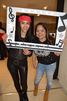 two women holding up a photo frame with musical notes on it