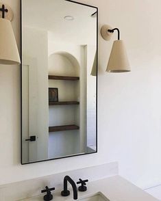 a bathroom sink sitting under a mirror next to a wall mounted faucet with lights on it