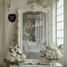 a welcome sign and flowers are sitting on a mantle in front of a mirror that says, welcome to the wedding of elizabeth & michael