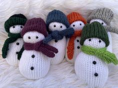 four knitted snowmen with hats and scarves on top of white furnishing