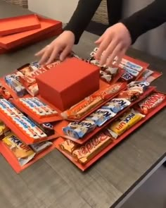 a person reaching for candy on top of a table with orange boxes and other snacks