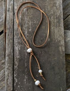 a brown leather cord with white beads on it and some wood planks in the background