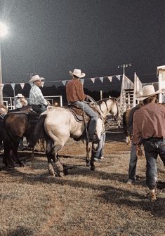 men in cowboy hats are riding horses on the field at night with flags and bunting