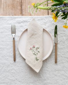 a white plate topped with a napkin next to a fork and knife on top of a table