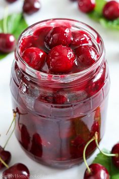 a jar filled with cherries sitting on top of a table