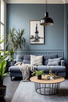 a living room with blue walls and grey couches, potted plants and pictures on the wall