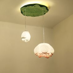 three lamps hanging from the ceiling in a room with white walls and green leaves on them