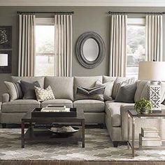 a living room filled with lots of furniture next to a window covered in drapes