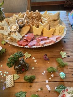 a plate full of crackers, cheeses and meats on a wooden table