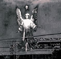 an angel statue on top of a building in the middle of the night with rain coming down