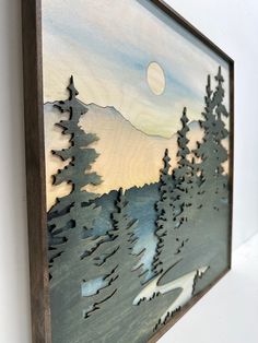 a painting hanging on the side of a wall with trees and mountains painted on it