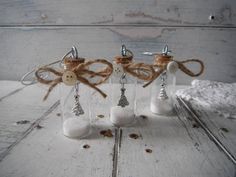 three glass bottles with white sand and brown twine tied to them, sitting on a wooden table