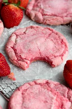 some pink cookies and strawberries on a table