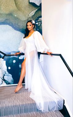 a woman in a white dress is standing on some stairs