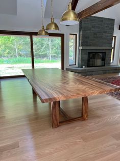 a large wooden table sitting in the middle of a living room next to a fire place