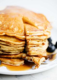 a stack of pancakes with syrup and blueberries