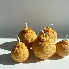 four oranges are sitting on a white surface with little strings attached to the top