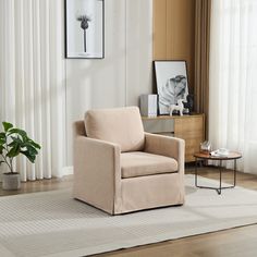 a living room with a chair, coffee table and pictures on the wall