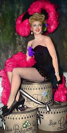 a woman in a black dress and pink hat sitting on top of two buckets