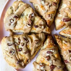 a white plate topped with scones covered in frosting and pecans on top of a wooden table