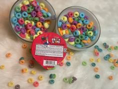 two plastic containers filled with colorful beads on top of a white surface next to each other