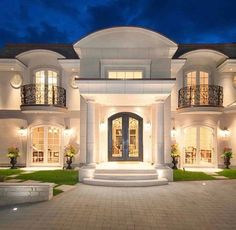 a large white house with lots of windows and lights on it's front entrance