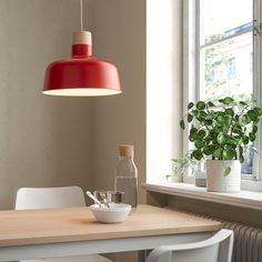 a dining room table with white chairs and a red light hanging over it