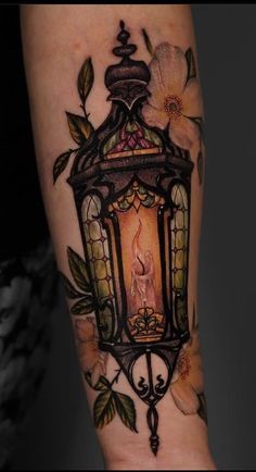 a lantern with flowers on it and a candle lite up in the middle of its arm