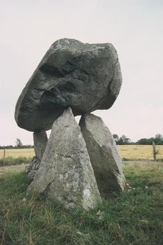 a large rock sitting on top of a lush green field