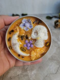 a person is holding a small bowl with food in it and flowers on the side