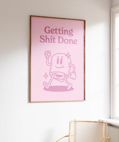 a pink poster hanging on the wall above a chair