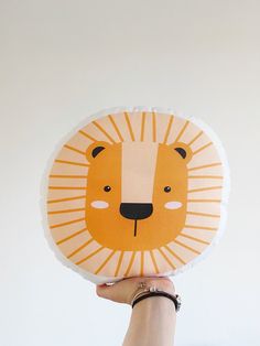 a hand holding up a paper plate with a lion design on it's face