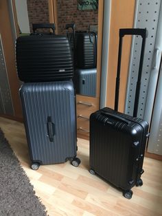 two black suitcases sitting next to each other on the floor in front of a mirror