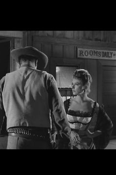 the man and woman are holding hands in an old western movie scene, one is wearing a cowboy hat