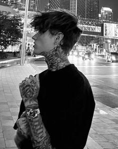 a woman with tattoos on her neck standing in front of a city street at night