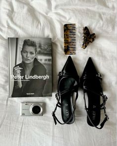 shoes, hair comb, camera and magazine laying on a bed