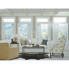 a living room filled with furniture and windows covered in white shuttered glass coverings