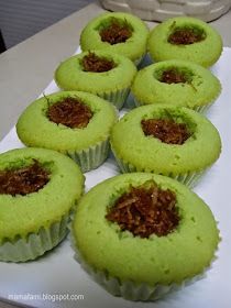 several green cupcakes are on a white plate with some brown stuff in the middle