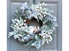 a wreath with white flowers and pine cones