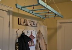 a coat rack with clothes hanging from it and a laundry sign on the wall behind it