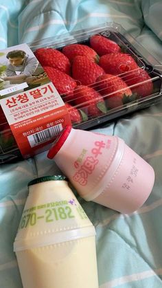 strawberries, milk and yogurt are sitting on a bed