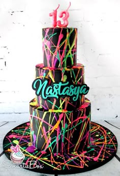 a three tiered birthday cake with neon sprinkles and the number thirteen on it