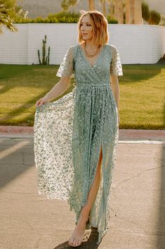 a woman in a green dress is walking down the street with her hand on her hip