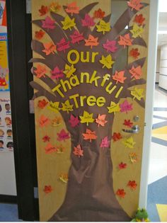 a door decorated with paper leaves and the words our thanksgiving tree written in yellow on it