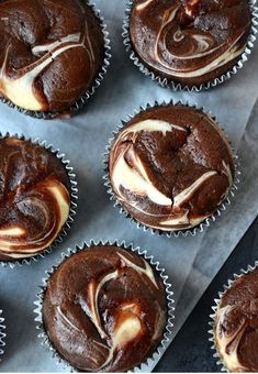 chocolate cupcakes with white frosting sitting on top of a baking sheet, ready to be eaten