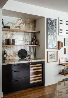 a kitchen with marble counter tops and shelves filled with wine glasses, liquor bottles and other items