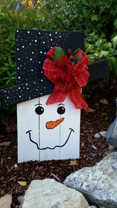 a wooden block with a red bow on it and a snowman face painted on it